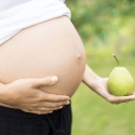 Mujer embarazada con una pera en su mano
