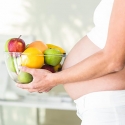 Mujer embarazada con fuente de frutas