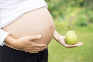 Mujer embarazada con una pera en su mano
