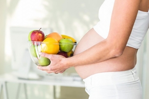 Mujer embarazada con fuente de frutas